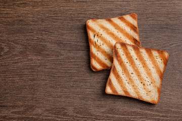 Slices of delicious toasted bread on wooden table, top view. Space for text