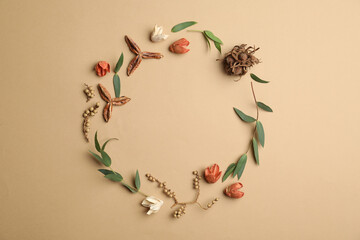 Dried flowers, leaves and seeds arranged in shape of wreath on beige background, flat lay with space for text. Autumnal aesthetic