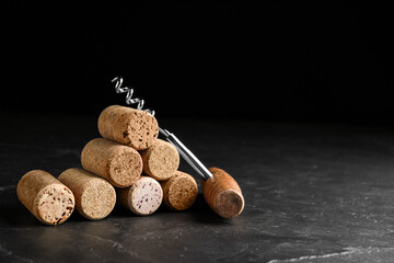 Corkscrew and stack of wine bottle stoppers on slate table. Space for text