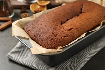 Delicious gingerbread cake in baking dish on grey table, closeup