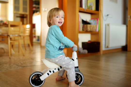 Funny Toddler Boy Riding A Baby Scooter At Home. Kid Training Balance On Mini Bike Indoors.