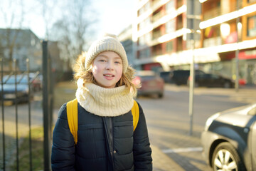 Cute young girl with a backpack heading to school on cold winter morning. Child going back to school.