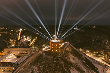 Scenic aerial view of Gediminas tower in Vilnius Old Town beautifully illuminated for 699 birthday celebration. Main symbol of Lithuanian capital at winter night.