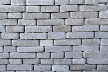 Defocus brick tiles stacked on a pallet. Gray pavement bricks for pavement road. Stack paving stones stacked in stacks. Gray design copy space. Brick background. Out of focus