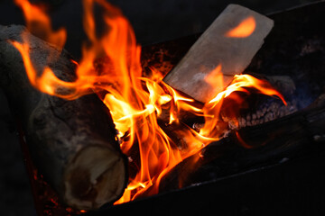 Defocus fire flame firewood fireplace wood. Bright flames burning wood on black background. Camp fire in the night. Out of focus