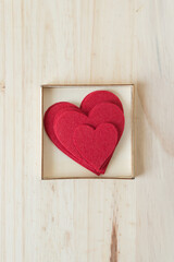 Plakat pile of felt hearts in a box on a wood surface
