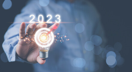 Businessman holding light bulb with target goals on hand to years 2023. Strategy marketing planning investment for a profit of the company. Ideas inspiration for investing in new businesses.