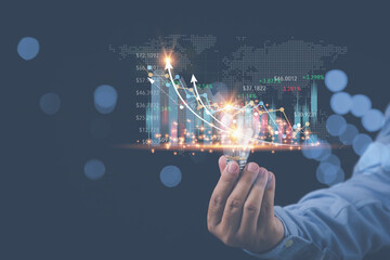 Businessman holding light bulb with growth a graph virtual screen on hand copy space. Business, Investment, and Finance concept. Analysis, strategy, and plan investments for business profit goals.