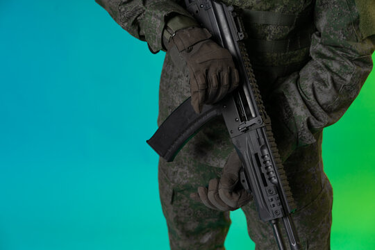 soldier in the studio on a green background with colored light. a man in military uniform with a gun, rifle or machine gun. military. airball player
