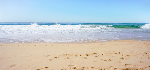 A sunswept panoramic scene with surf waves from the Pacific Ocean crashing onto a sandy shore on the Sunshine Coast, Australia. An idyllic location for a romantic or relaxing holiday.