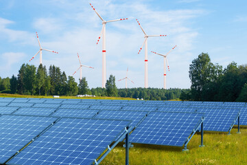 Solar panels under windmills. Wind power plants in sunny weather. Renewable energy. Solar panels to...