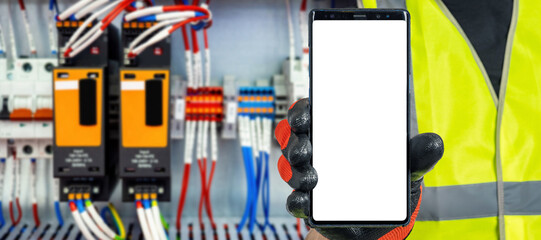 IOT electrical equipment. Phone template in hand. Place for IOT apps in smartphone. Hand electrician in front electrical panel. Concept controlling electrical appliances through phone. IOT template
