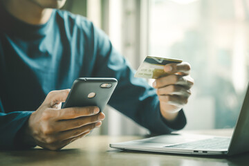 Man holding credit card and using smartphone at home online shopping ecommerce internet banking spend money work from home concept.