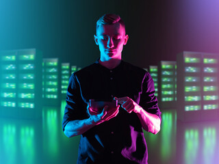 Young IT specialist. Man manager IT company. Control of server hardware via tablet. IT specialist with tablet computer. Blurred server equipment behind man. Server maintenance service concept