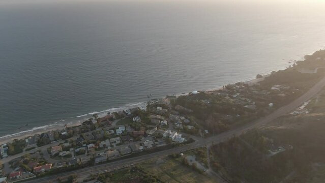 High angle aerial looking down on Malibu hills beachfront mansions at sunset