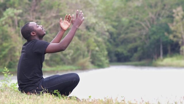 African man praying to thanksgiving in beautiful fields and nature