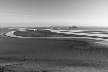 Beautiful sunset over the beach during low tide, grayscale shot