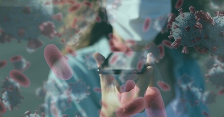 Covid-19 cells against woman wearing face mask talking on smartphone