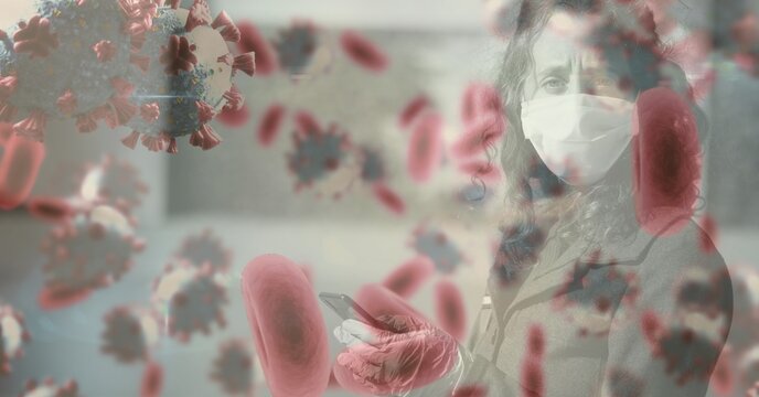 Covid-19 cells against woman wearing face mask using a smartphone