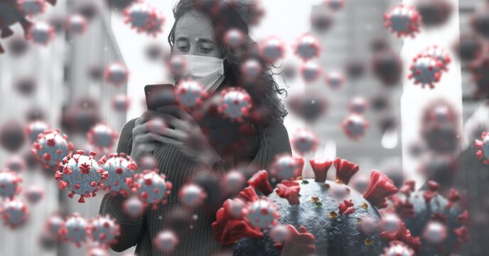 Covid-19 cells against woman wearing face mask using smartphone