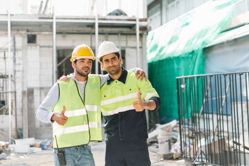 Fototapeta na wymiar Two standing construction engineers don safety jackets and helmets on construction site, Working Safety at Workplace Concept