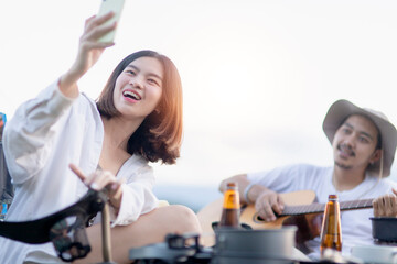 Happy Asian Couple Play guitar and sing enjoy camping and drinking beer.