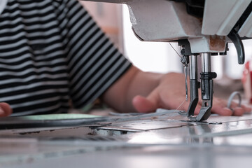The seamstress sews at the sewing machine, threads the fabric. Women's hands