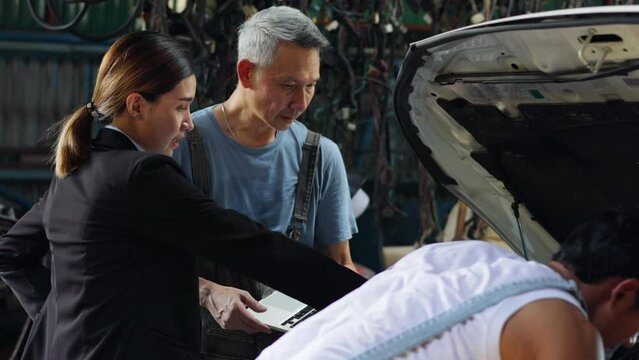 Serious asian young woman customer talking with owner and mechanic worker at car repair service and auto store shop.