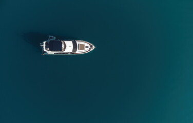 Aerial yacht on calm sea. Luxury cruise trip. View from above of white boat on deep blue water....