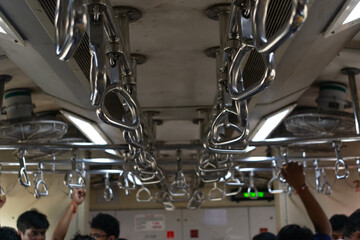 People standing inside of carriage holding handles in Mumbai's local train. Carriage, handles,...