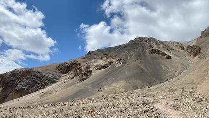 Beautiful mountain landscape. Blue sky and white clouds. Rocky mountains, hills and trails of Kyrgyzstan.