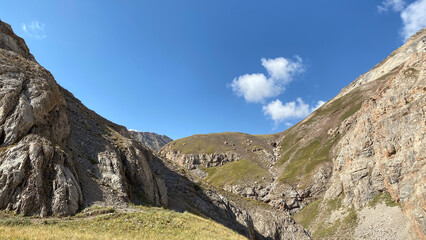 Summer mountain landscape. Green hills and slopes of Kyrgyzstan. Blue sky and white clouds.