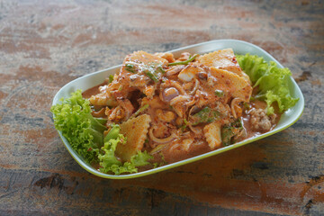 closeup hot young coconut shoot salad with minced pork on green plastic plate on wooden floor background, copy space