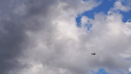 The passenger airplane is flying far away in the dark clouds. Aircraft in the air. International passenger air transportation