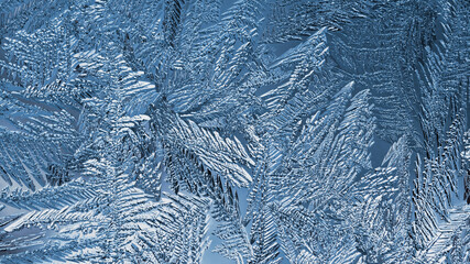 Abstract Christmas background. Ice crystals on frozen window glass. Frost drawing. A pattern of leaves and stems of magical fantastic plants. Blue tinted winter wallpaper. Cold and crystal. Macro