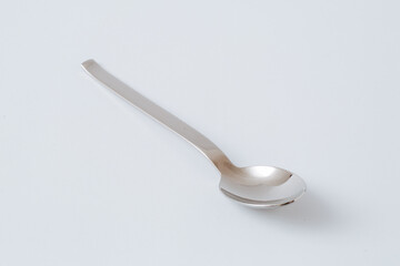 Stainless steel teaspoon on white background, kitchenware, copy space, close-up
