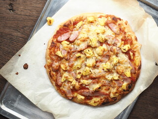 Top view whole piece of pizza with pineapple and sausage topping in baking tray