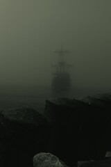 Vertical shot of pirate ship entering the port on a foggy day