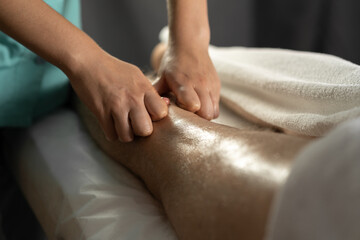 Sports massage. Female physiotherapist massaging the legs of a young male athlete. close-up masseur hands doing foot massage.