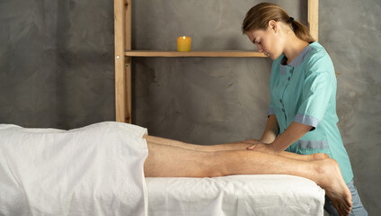 Female therapist giving leg massage to athlete patient on the bed in clinic or spa. sports physical therapy