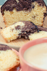 Cup of coffee with milk and fresh baked yeast dough with cocoa and chocolate icing. Delicious dessert