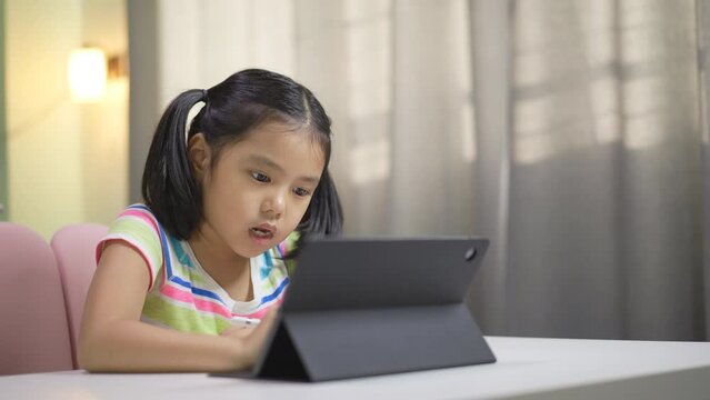 asian child student drawing learning on computer tablet screen by touch pen studying or kid girl fun writing or art draw on study online class by video call talking or person learn from home school