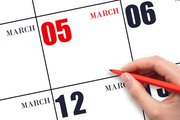 A hand holding a red pen and pointing on the calendar date March 5. Red calendar date, copy space,...