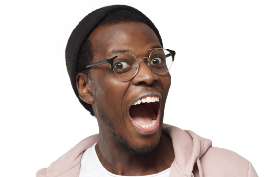 Emotional African man wearing trendy round eyeglasses looking at camera with eyes and mouth wide open surprised with pleasant news