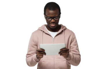Studio closeup of young African American man pictured wearing eyeglasses looking attentively to screen of tablet he is holding