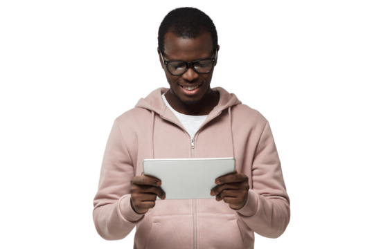 Studio closeup of young African American man pictured wearing eyeglasses looking attentively to screen of tablet he is holding