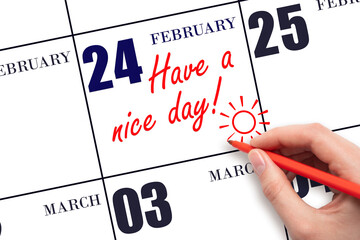The hand writing the text Have a nice day and drawing the sun on the calendar date February 24