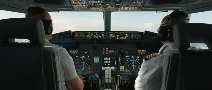 Commercial aircraft pilots adjusting flight parameters of the plane during the flight at high altitude. View from inside the cabin. Real aircraft, daytime shot