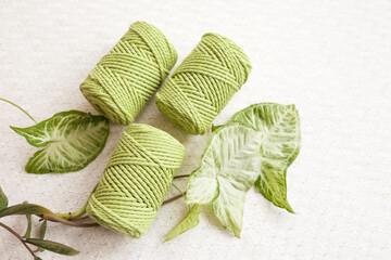 Handmade macrame braiding and cotton threads on white textile background. Green cotton macrame...