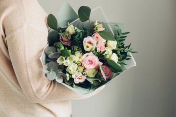 Woman holding fresh blossoming flower bouquet of beautiful flowers in pastel pink colour